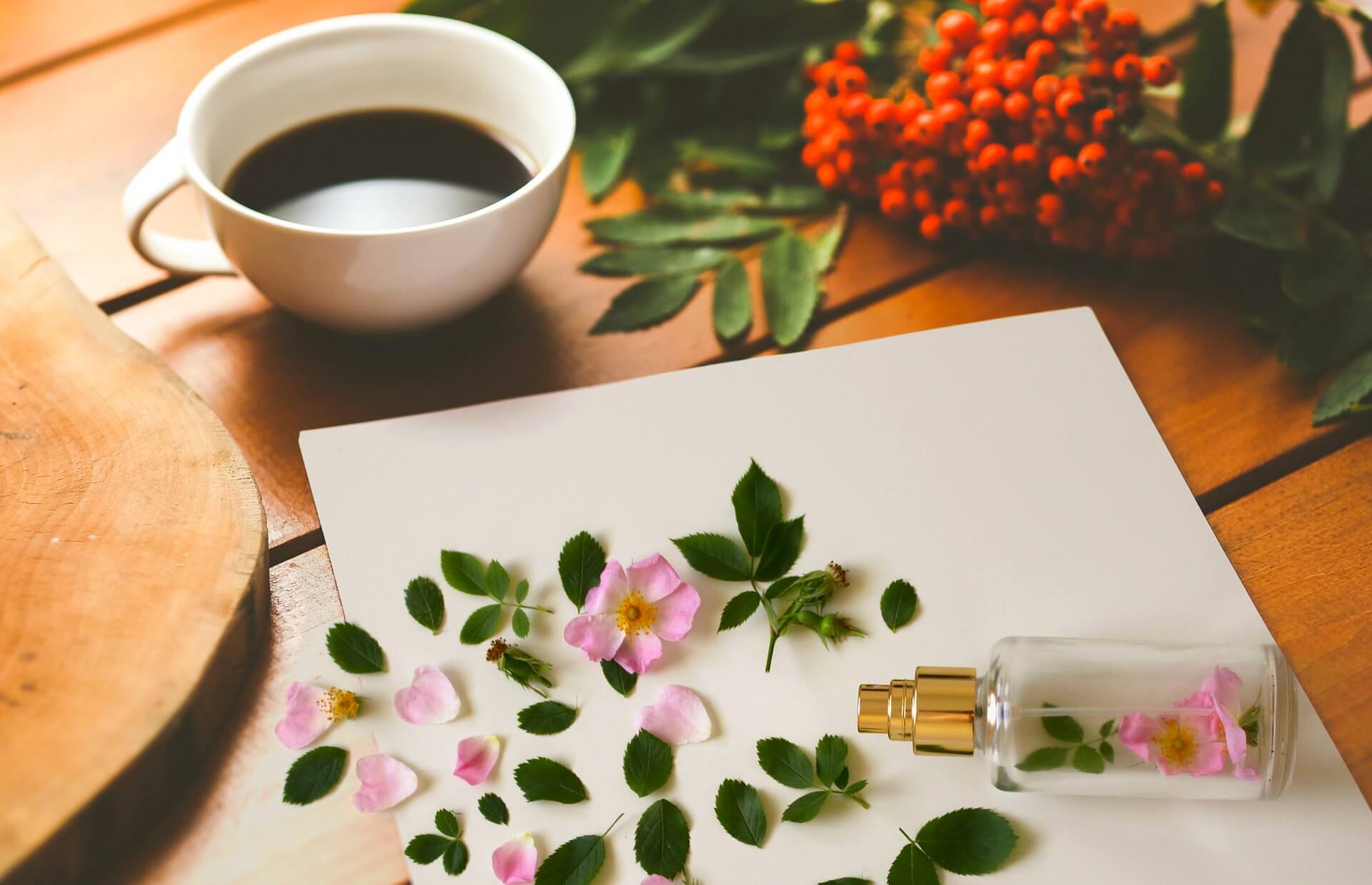 perfume bottle with some leaves and a petals with some foliage and a coffee